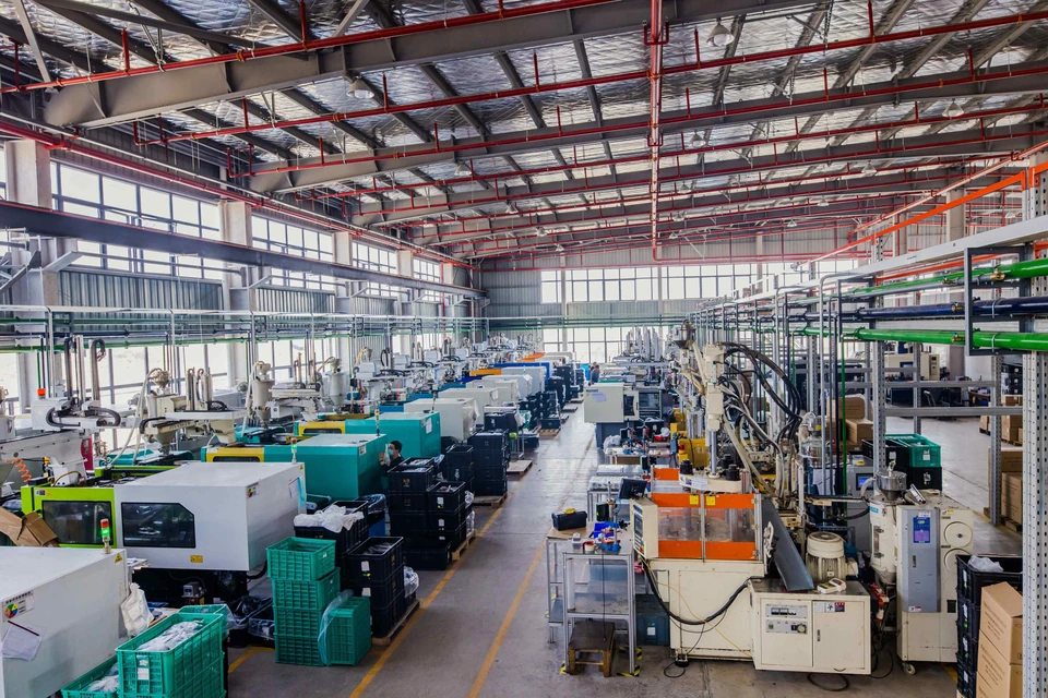 Rows of injection-molding equipment, service pipes and handling containers along a workshop aisle