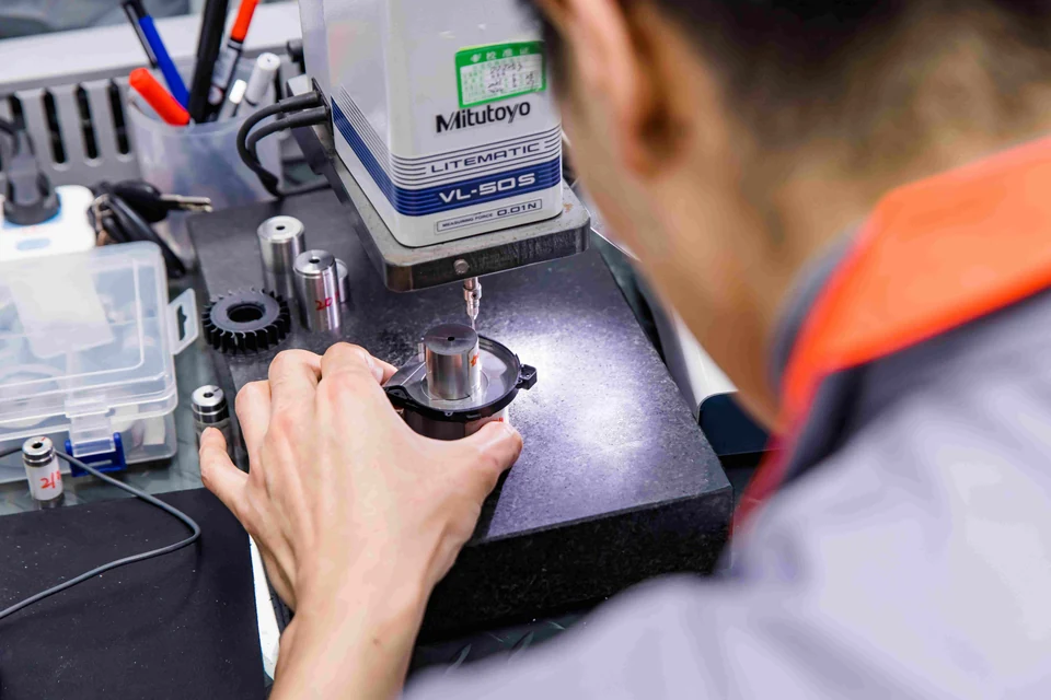 A person reviewing a component beside equipment