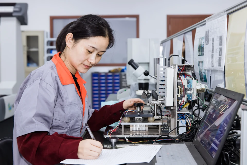A Dongying measurement and recording scene with an operator, tabletop equipment and paper records